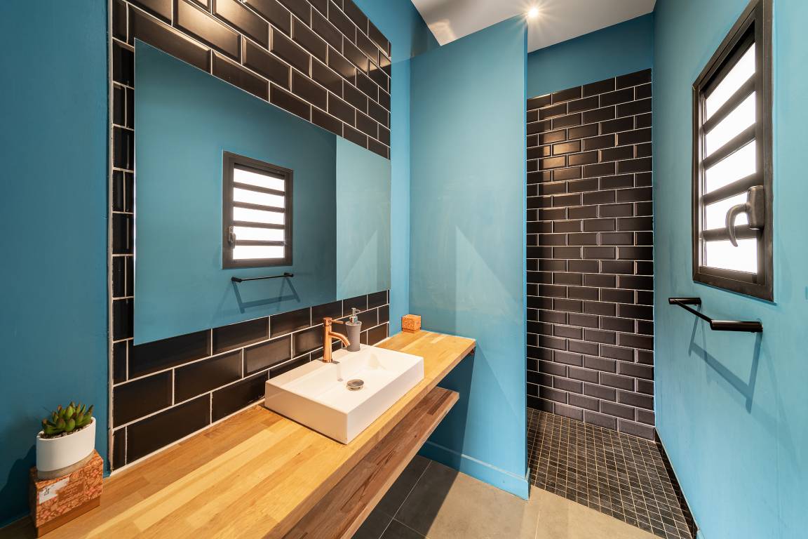 Salle d’eau aux murs turquoise avec douche à l’italienne en briques sombres