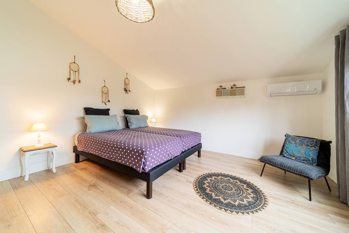 Chambre mansardée avec lit double, tons pastel et parquet clair