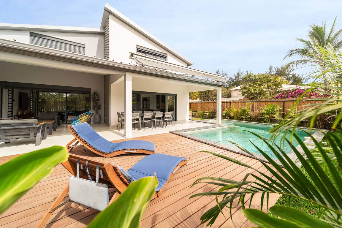 Villa Jélys avec terrasse couverte, transats bleus et piscine au cœur du jardin
